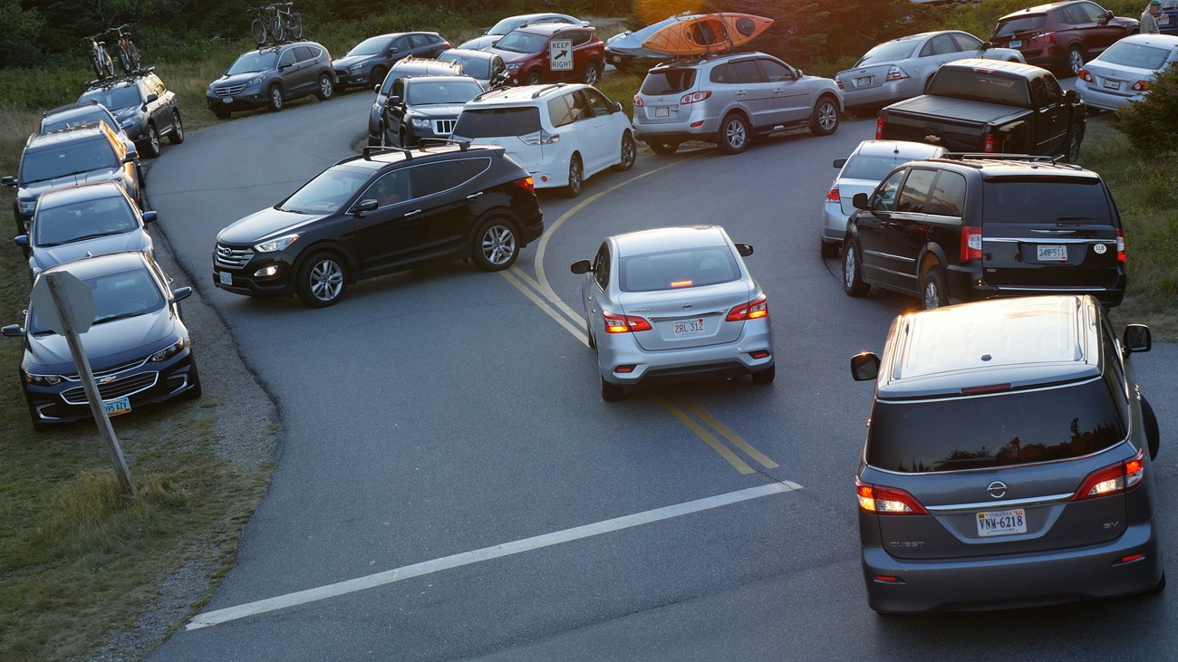 Automobiles jockey for parking spots in a narrow and crowded corner.