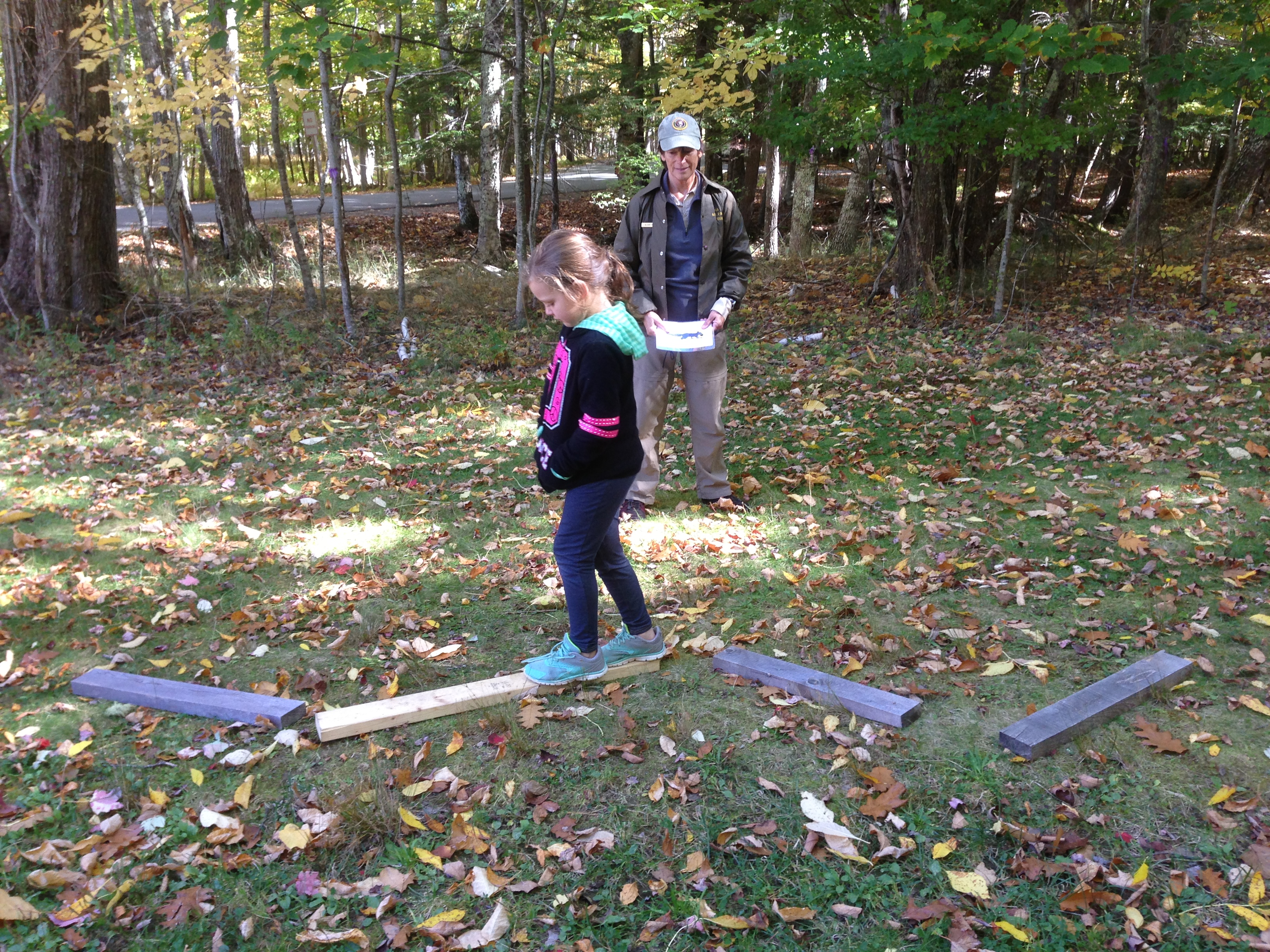 Student balances on beam while ranger looks on. 