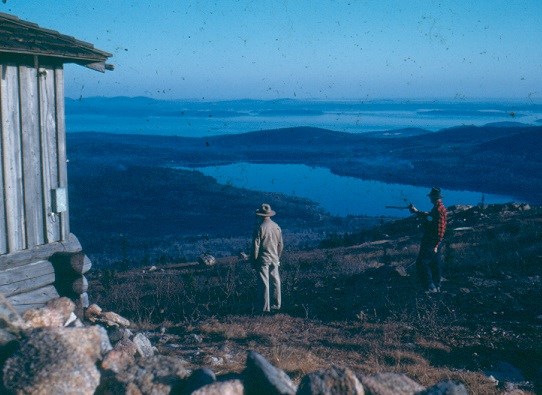 Historic photograph of two people standing by a fire lookout