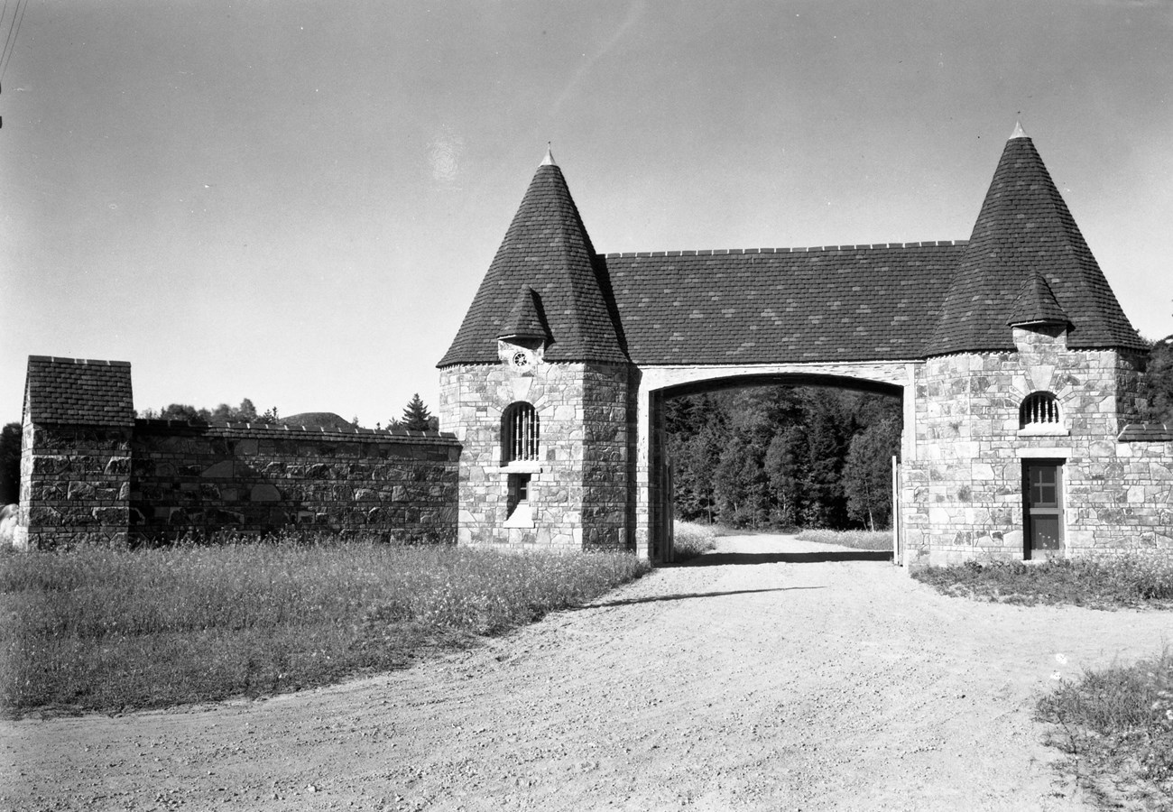 Stone gate and wall in front of a gravel road