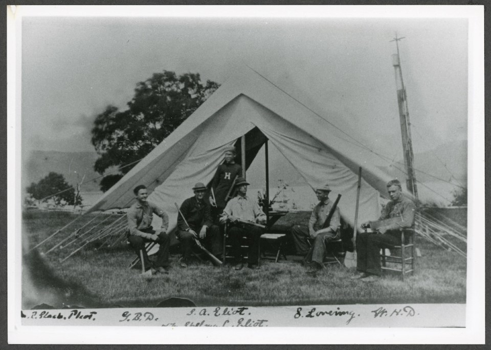five men posing for a picture in front of a tent