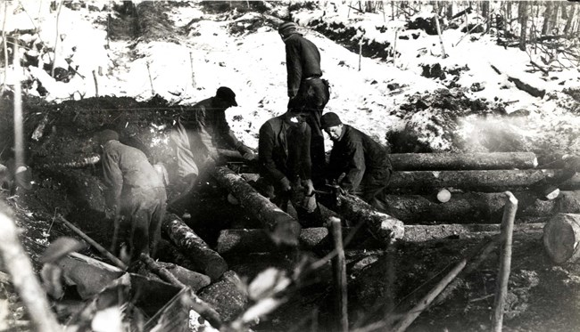 Workers building a wooden bridge in a forested area