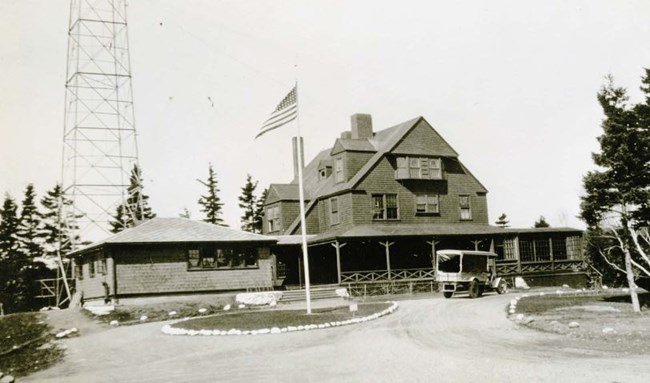 a radio tower and large farm house style building in black and white
