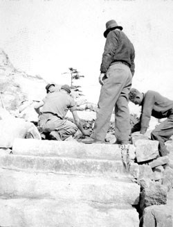 B&W photo looking up stone steps at men working