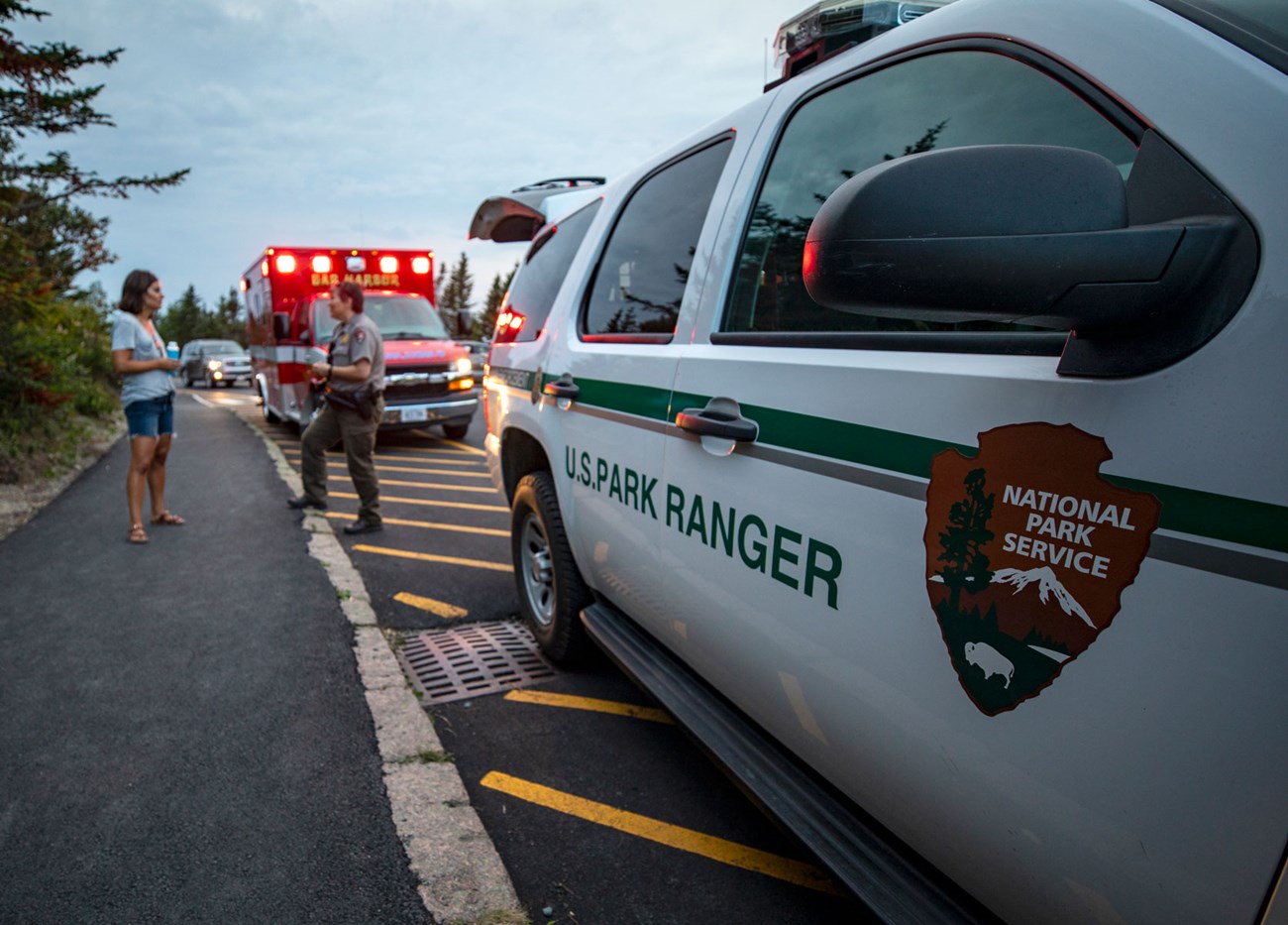 A female ranger and female visitor talk in front of emergency vehicles