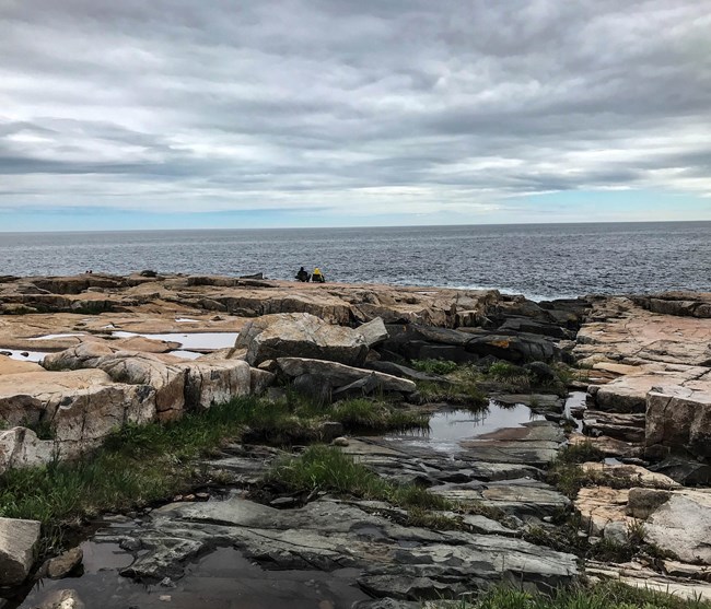 Two visitors sit along the stormy shores at Schoodic Peninsula
