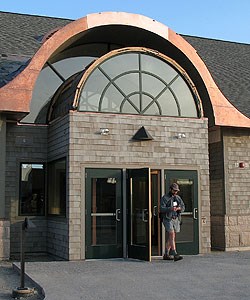 Man walking out of the main entrance of the Moore Auditorium Man walking out of the main entrance of the Moore Auditorium