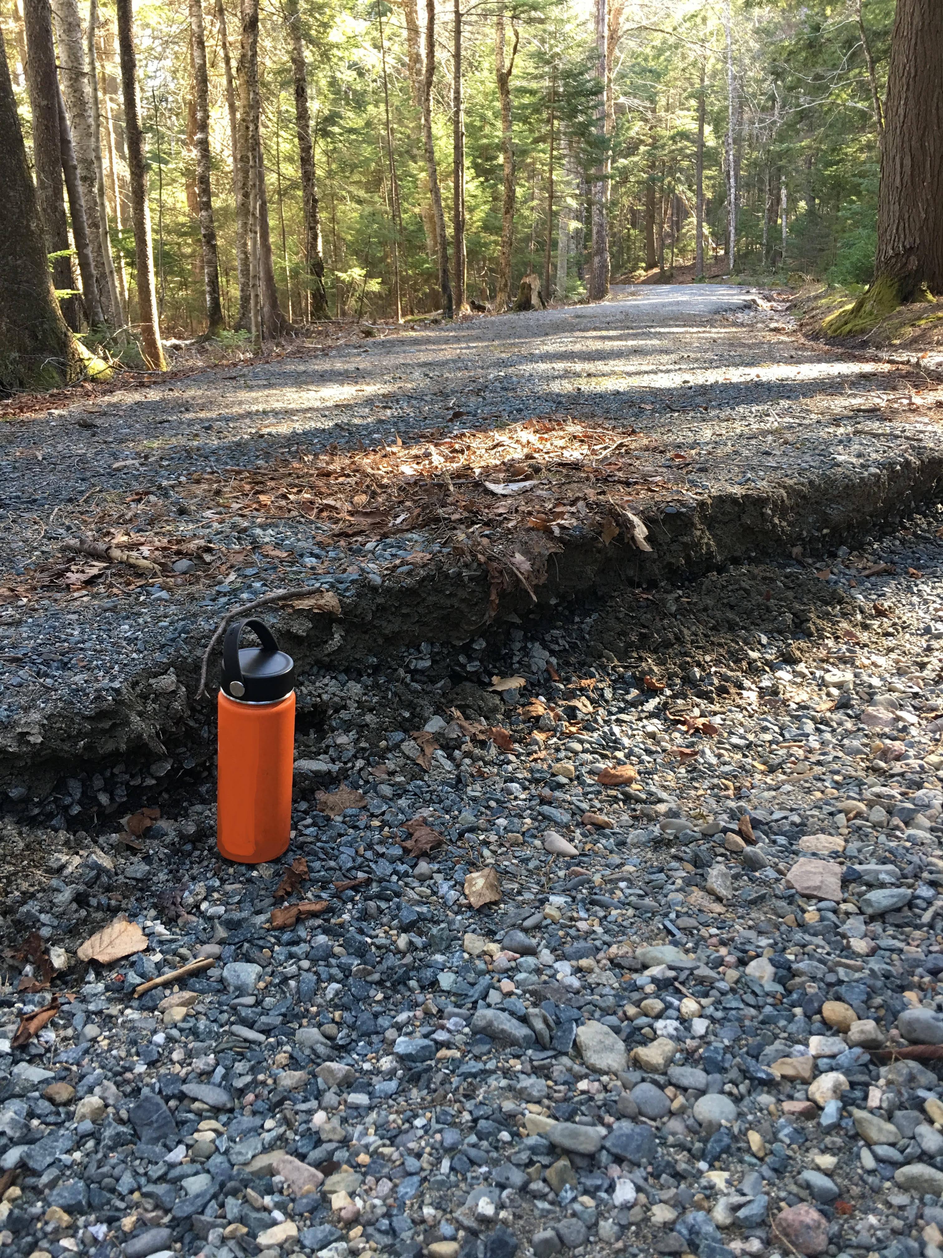Damaged road with asphalt crumbling sharply to gravel