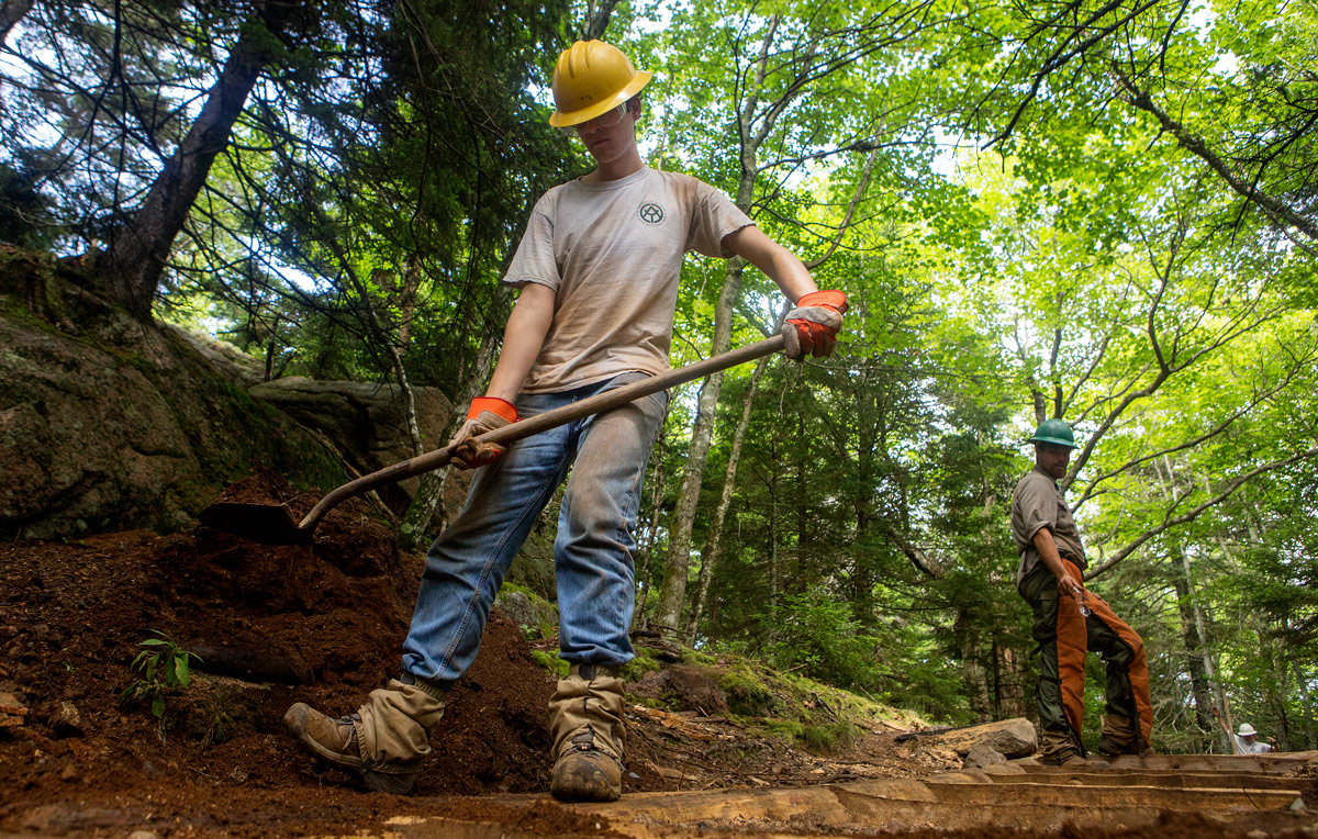 Trail worker holding a shovel and wearing a yellow hard hat Trail worker holding a shovel and wearing a yellow hard hat