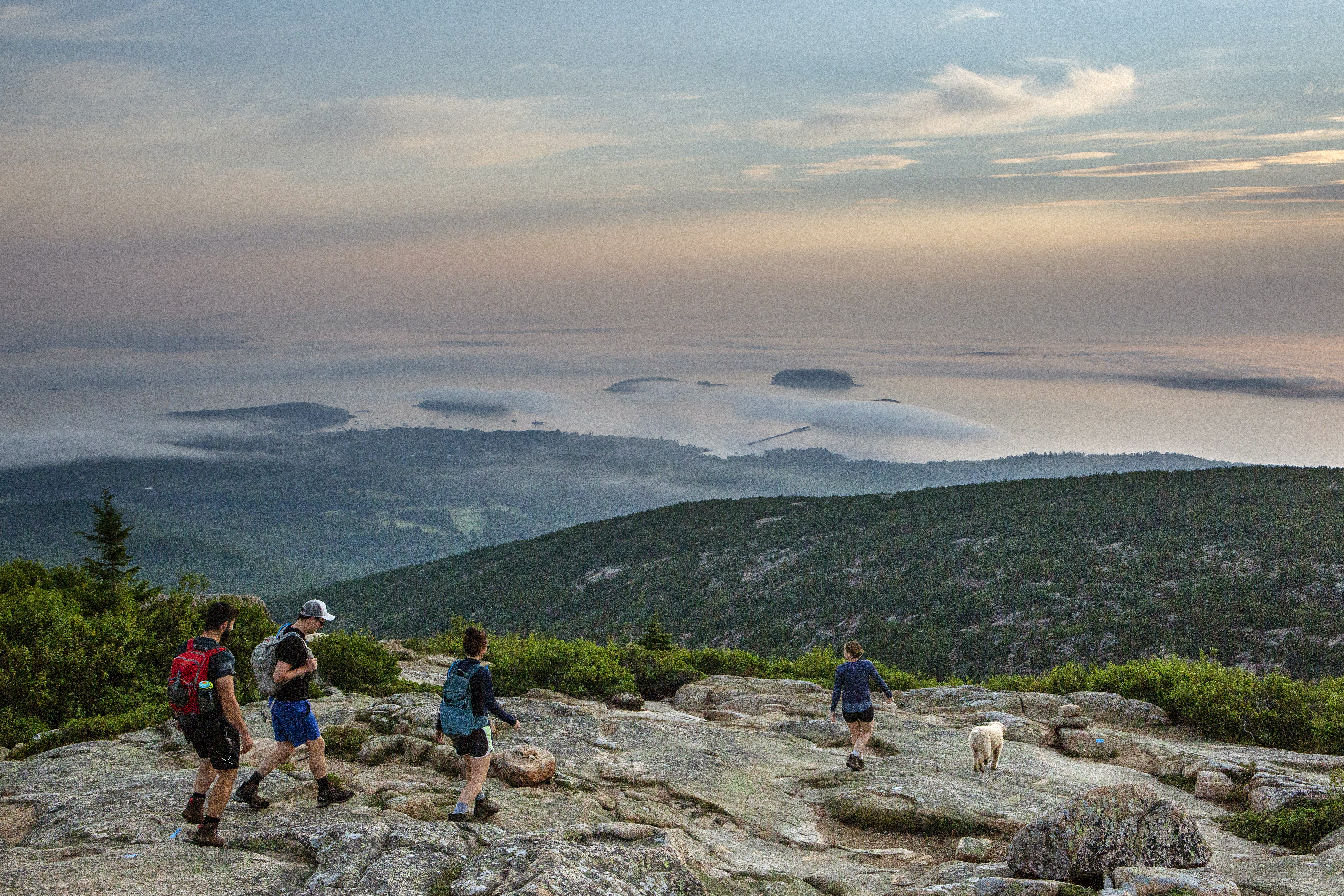 Cadillac South Ridge Summit Visitors watch as the rising sun illuminates foggy Porcupine Islands from Cadillac Mountain in Acadia National Park