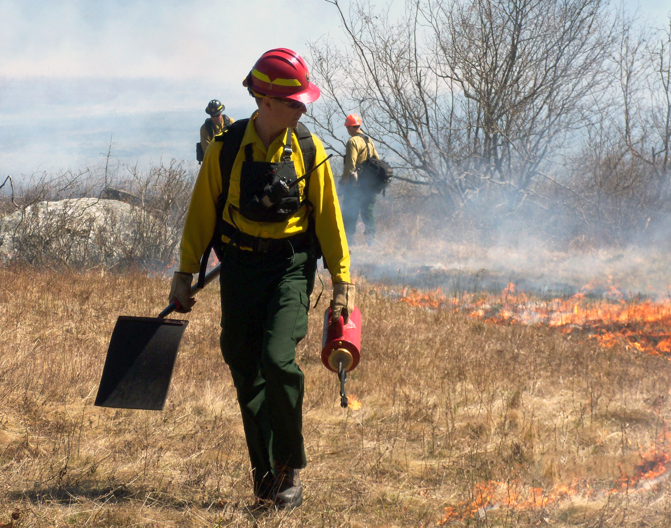 Willdland firefighter carries a drip torch