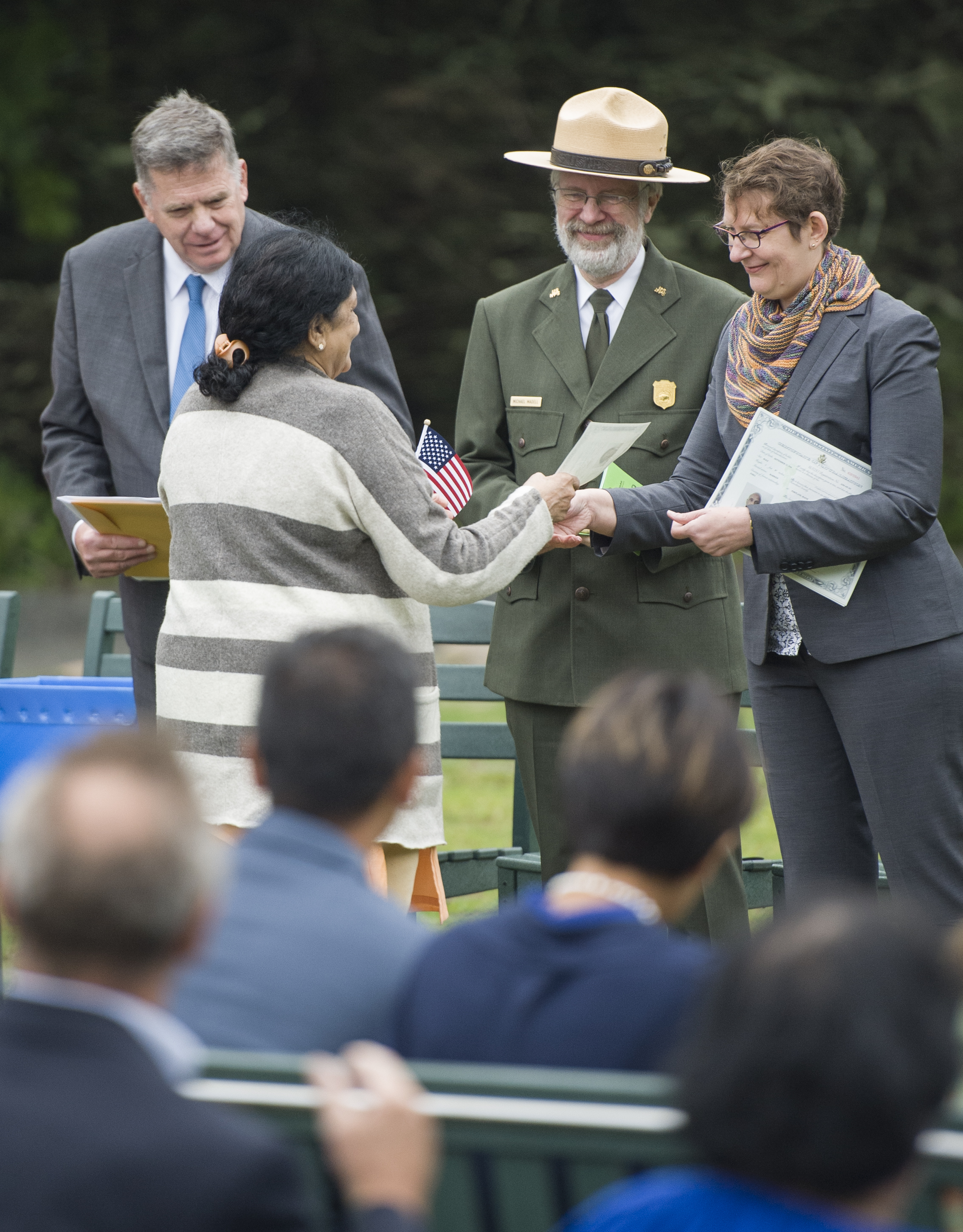 Two men and a woman in a receiving line welcome a new U.S. citizen