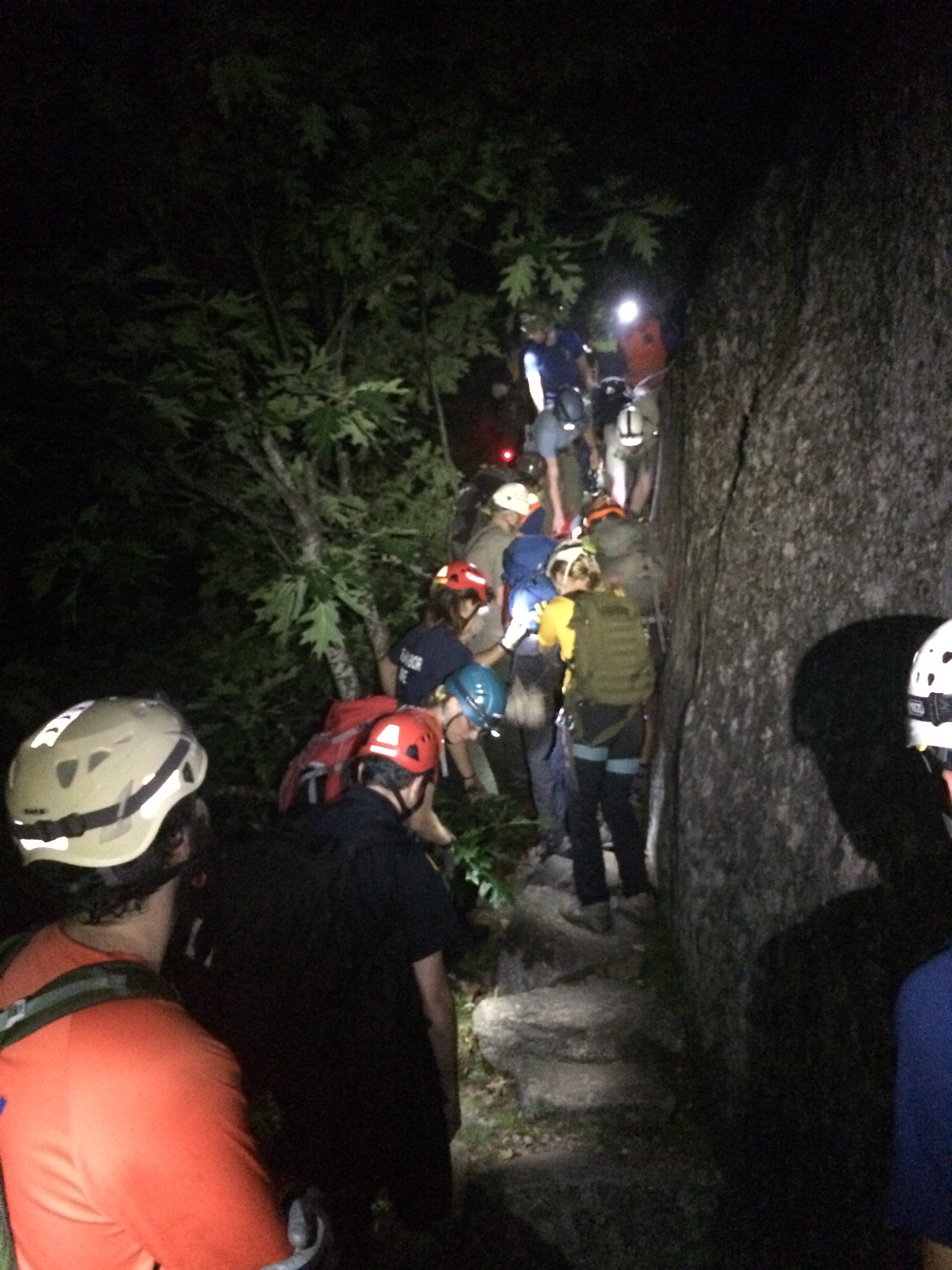 Rescuers on narrow trail along steep rock face