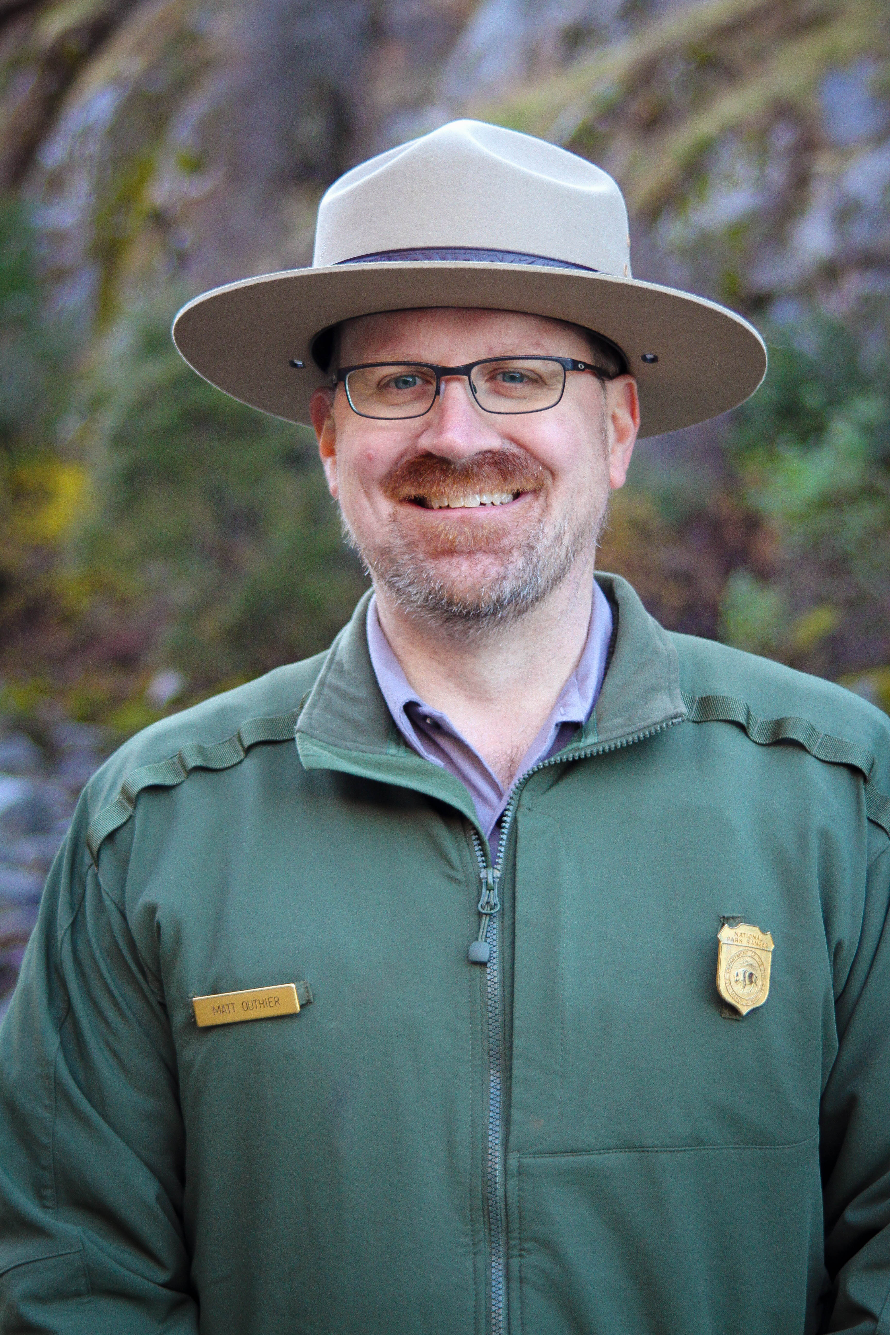 Matt Outhier A man with a grey and red beard dressed in ranger uniform smiles directly at the camera.