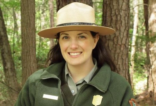 Joy Absher A person who presents as female smiles at the camera. She wears a park ranger uniform and flat hat.