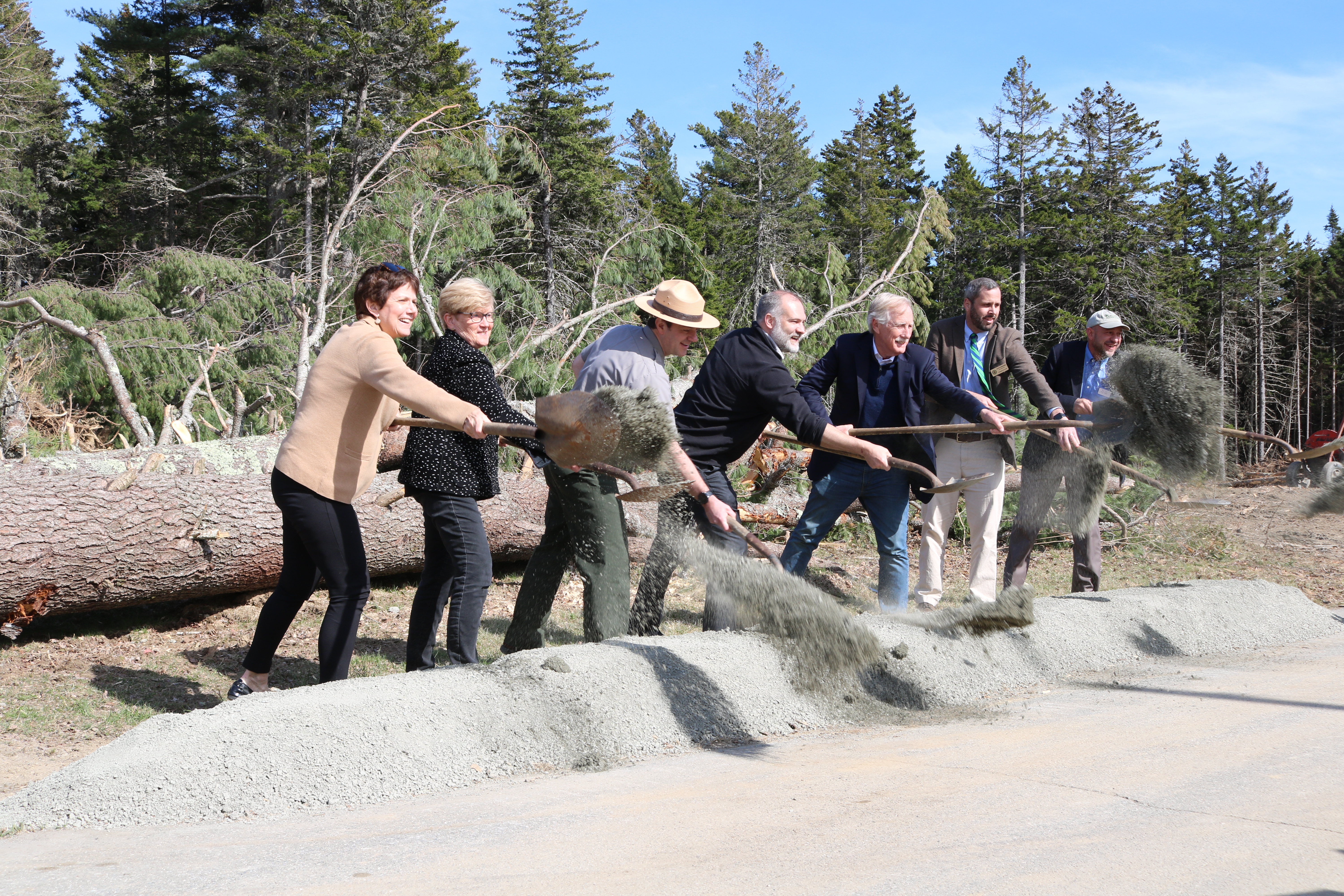 7 individuals throw dirt from their shovels, ceremoniously breaking ground on the new maintenance facility.