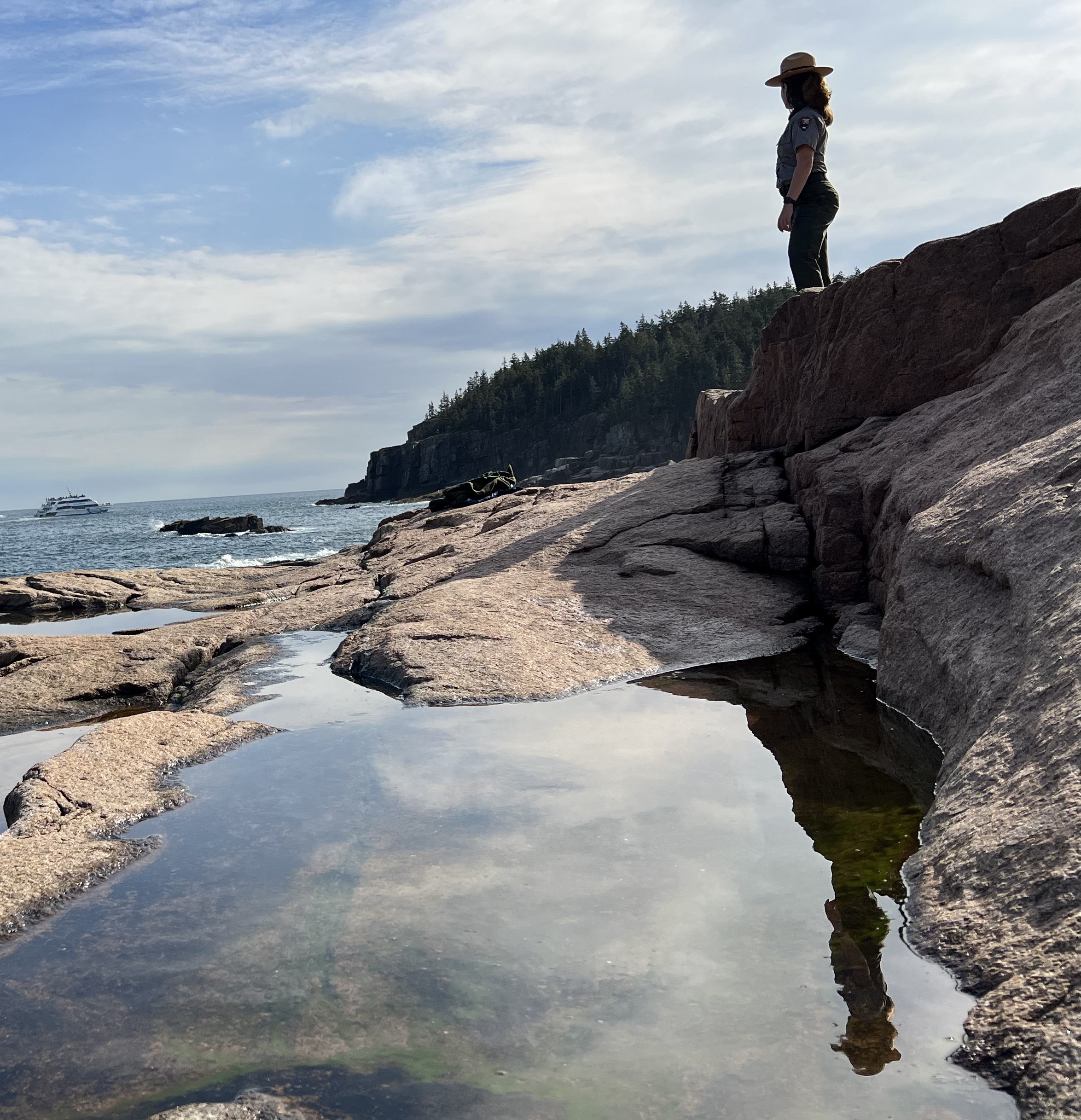 Ranger stands looking over her shoulder at Otter Cliffs.