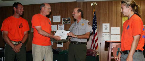 Three volunteers accept an award from the park superintendent.