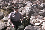Park ranger crouches in rocks