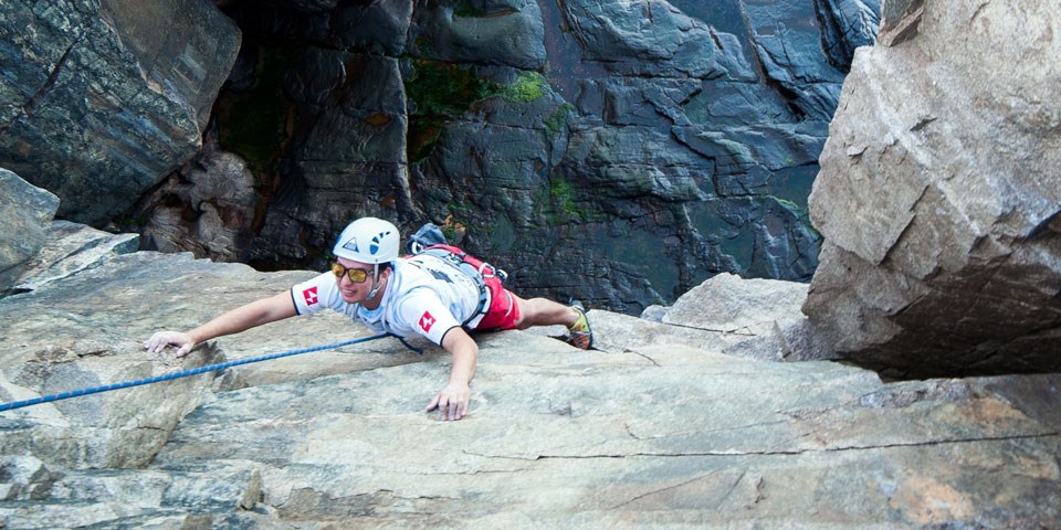 Man on rope clings to vertical rock face