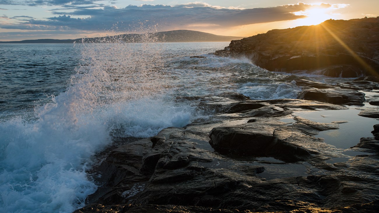 Waves crash on rocky coastline at sunset