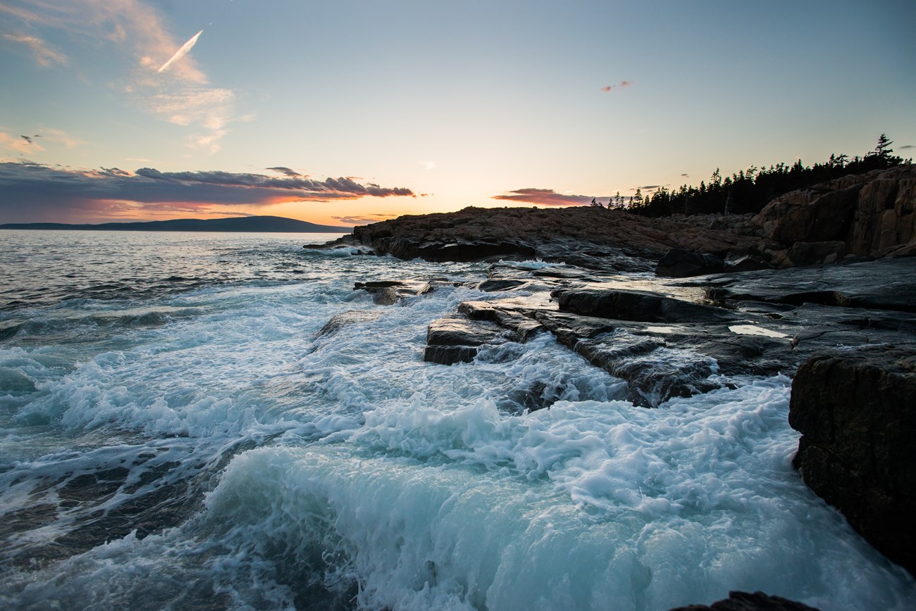 Waves crashing over a rocky coastline at sunset