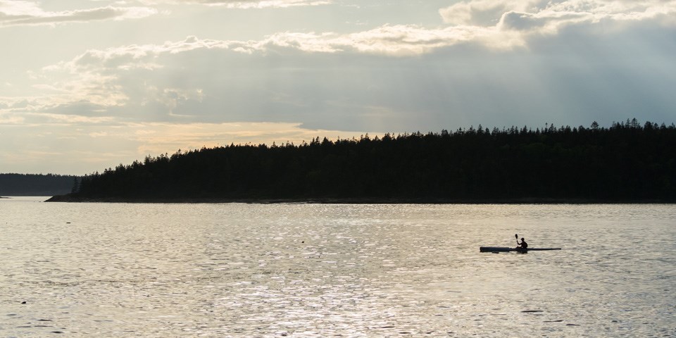 Person in kayak paddles on vast open water