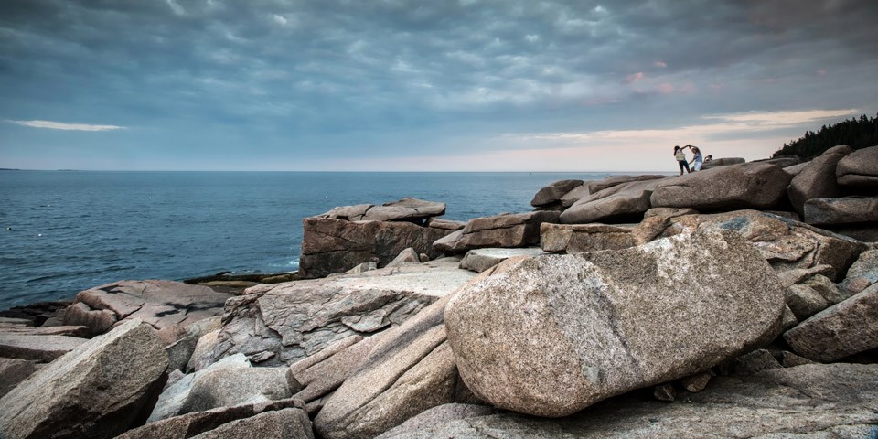 Two visitors dance along coastline boulders of Ocean Path Two visitors dance along coastline boulders of Ocean Path