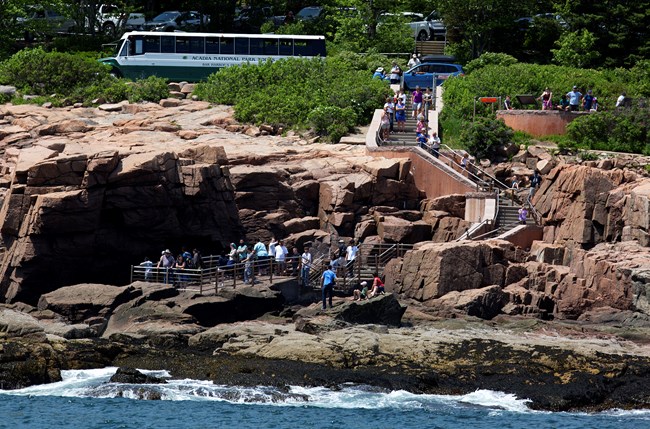 People walk down stairs from road to coastline