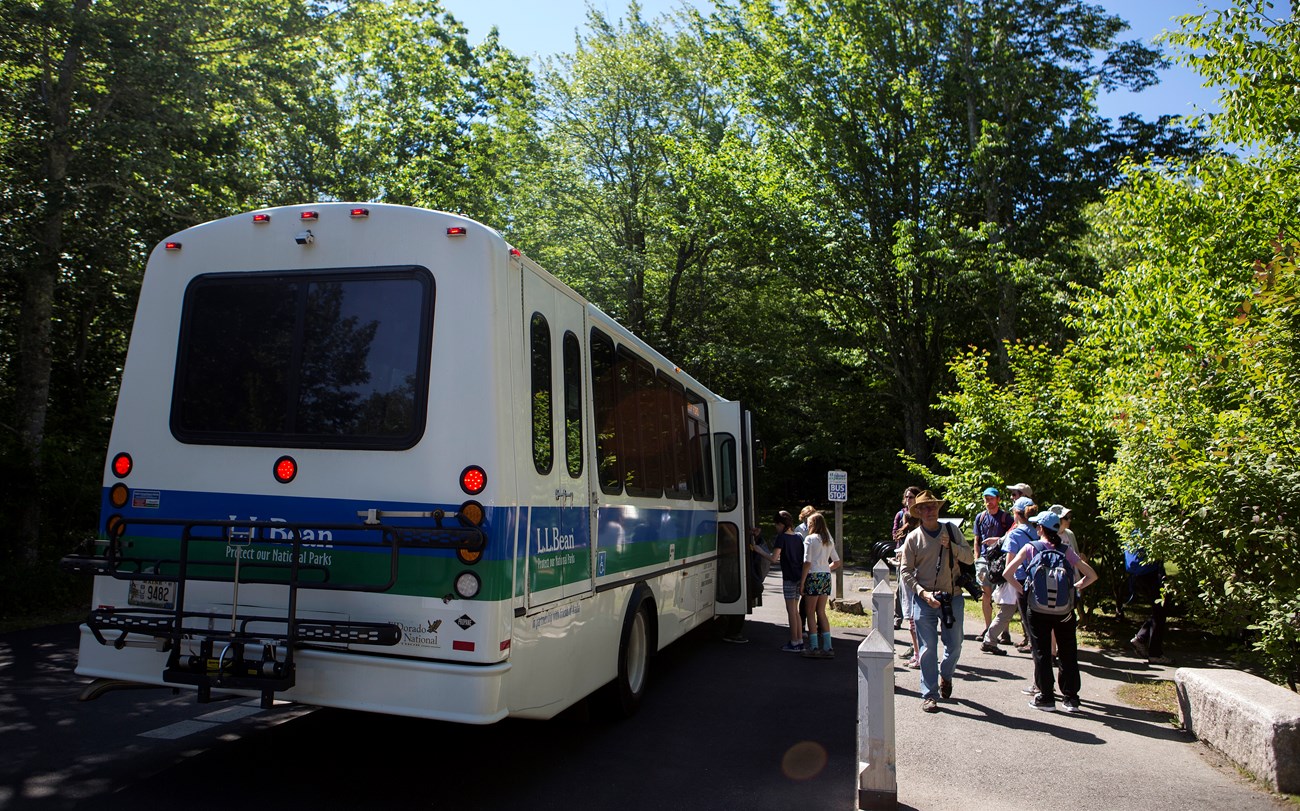 White bus letting passengers off on a sidewalk