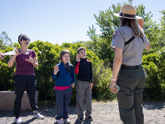 a ranger swears in two children with mom standing by