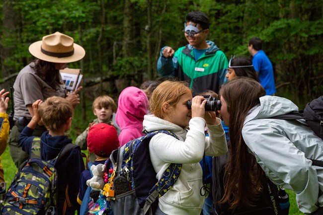 a ranger surrounded by kids in animal masks