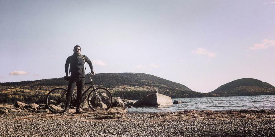Man stands beside bicycle by lake shore Man stands beside bicycle by lake shore