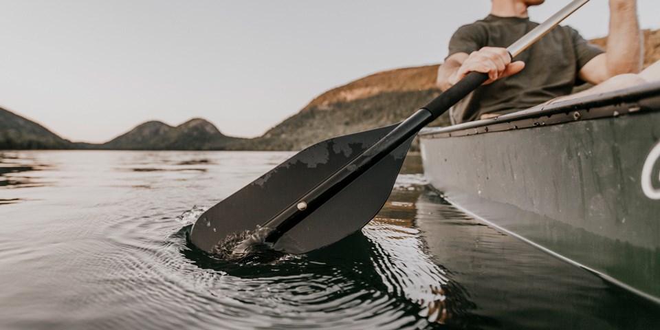 Man paddles a canoe on a still pond Man paddles a canoe on a still pond