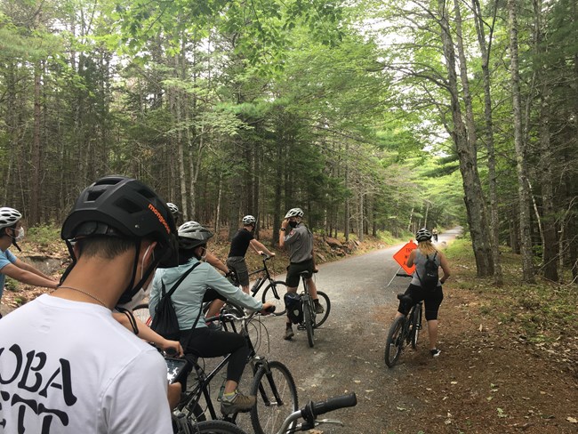 a ranger stands next to a bike talking to visitors on the carriage roads