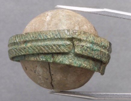 A clay ball with a copper-alloy band.