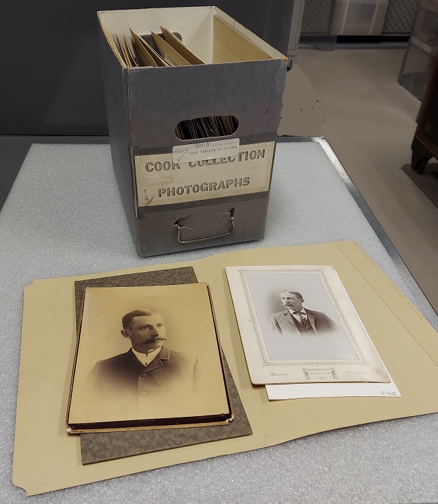 James H. Cook in the 1870s. 2 historical photos rest in front of a file box labeled, "Cook Collection Photographs."