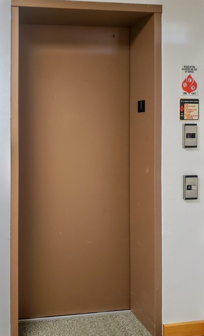 Brown elevator door with control buttons to right
