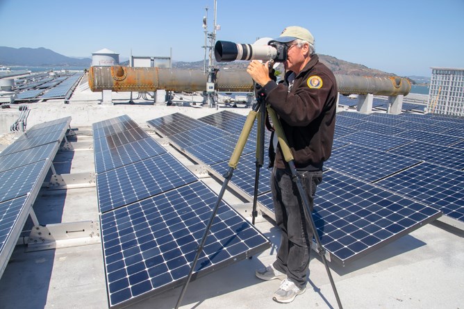 man on top of roof with tripod camera man on top of roof with tripod camera