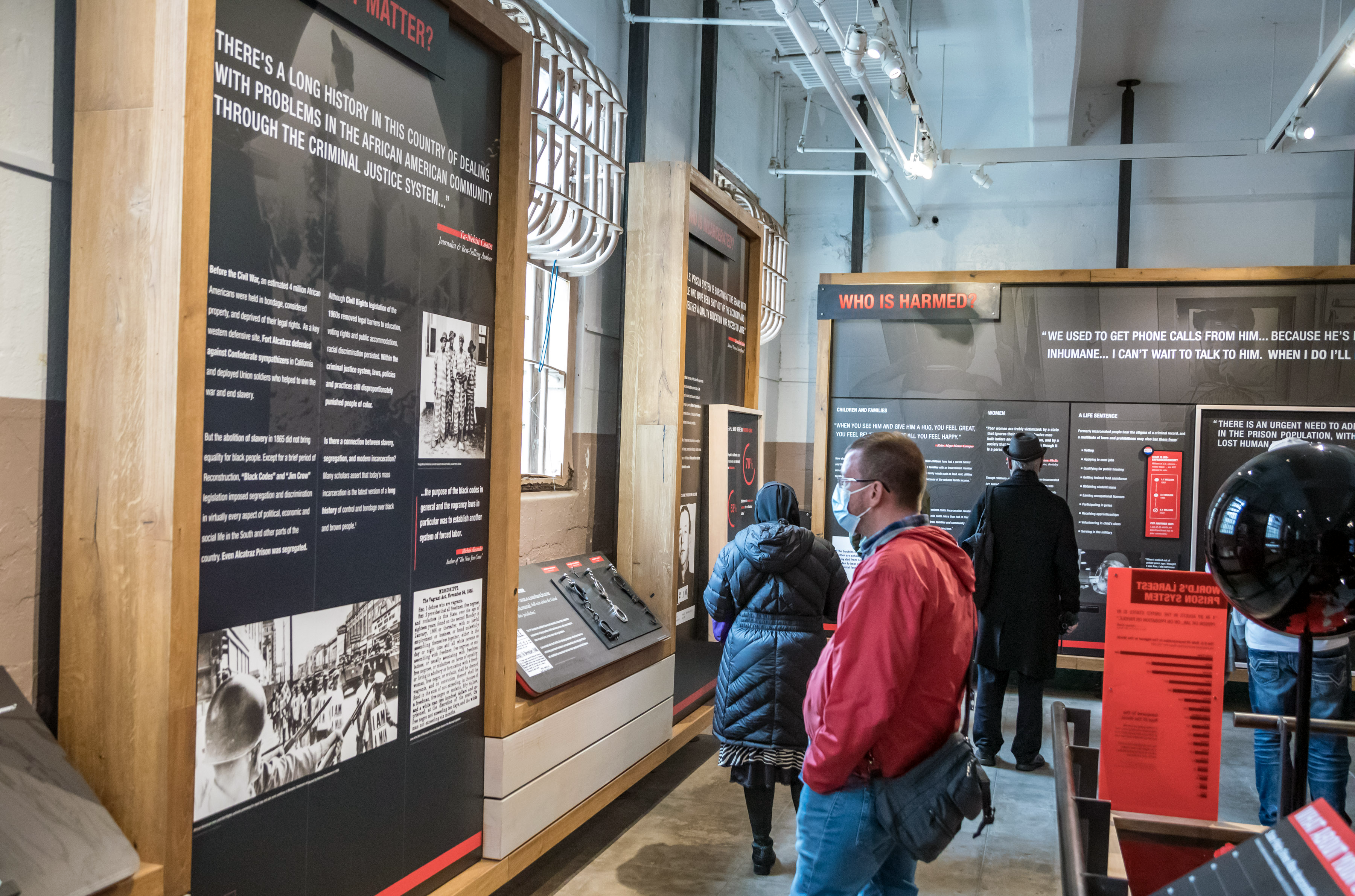 Visitors observe the panels of The Big Lockup: Mass Incarceration in the United States exhibit. The panels include text, images, and quotes from history to who is harmed by mass incarceration.