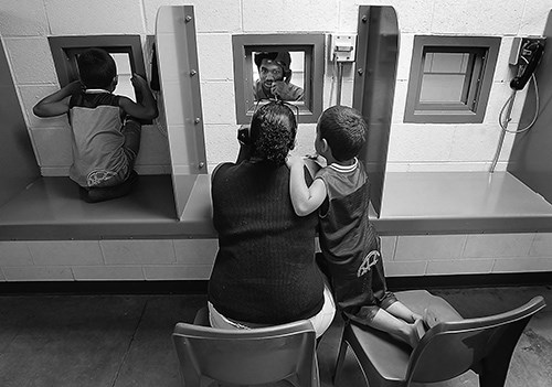 當五歲的雙胞胎孩子在納特羅納縣看守所探視室內跑動時，母親（中）與兒子在交談。獲得「星際論壇報」[Star Tribune]Dan Cepeda許可展出該相片。