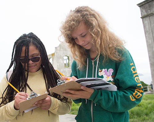 Two students write on clip boards at Alcatraz