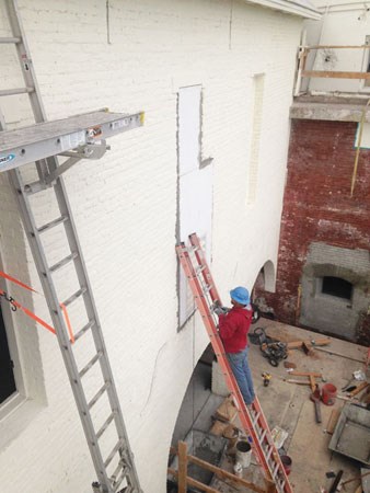 man on ladder working on brick wall