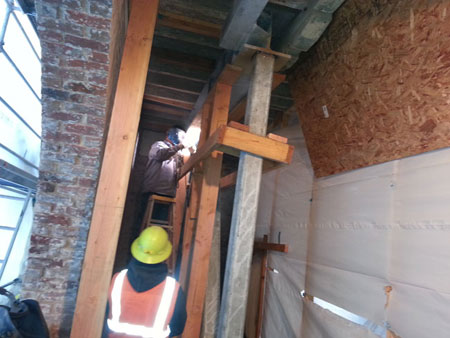 men with hard hats working inside cramped brick wall