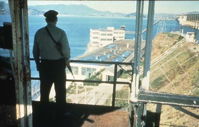 Armed correctional officer in guard tower.