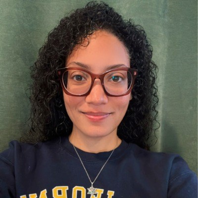 Woman with curly hair, glasses, and UC Berkely sweatshirt takes a selfie.