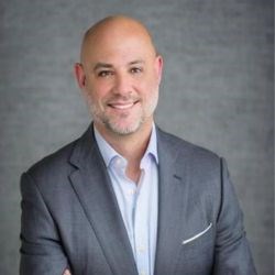 Portrait of bald man in grey suit with salt and pepper beard.