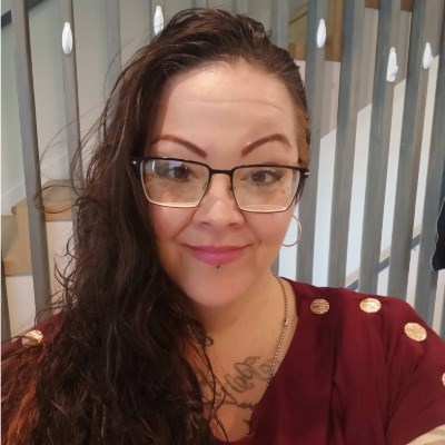 Brunette woman in glasses takes a selfie.