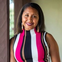 Black woman in pink, black, and white striped shirt smiles at camera