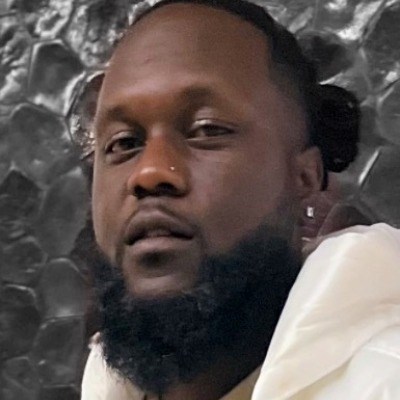 African American man with a beard and nose piercing smiles at camera